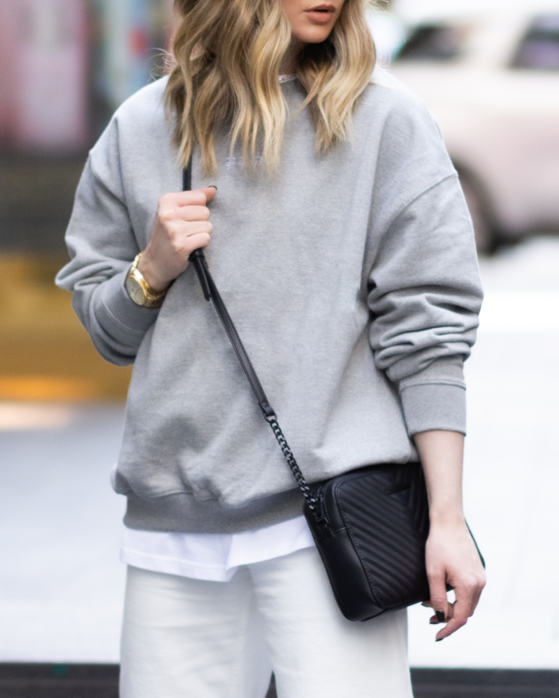 Female model wearing a heather grey sweatshirt in 100% cotton.
